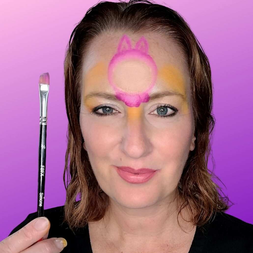 Omlijnen van het gezichtje van Labubu met splitcake en het zetten van oren en vachtje, als onderdeel van de Halloween schmink tutorial