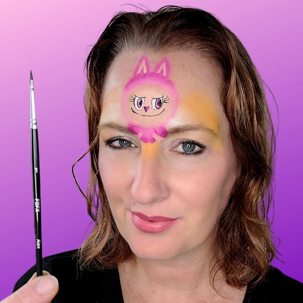 Omlijnen van het gezichtje en vacht van Labubu met zwarte schmink en dun penseel, voor een speels en herkenbaar monstertje