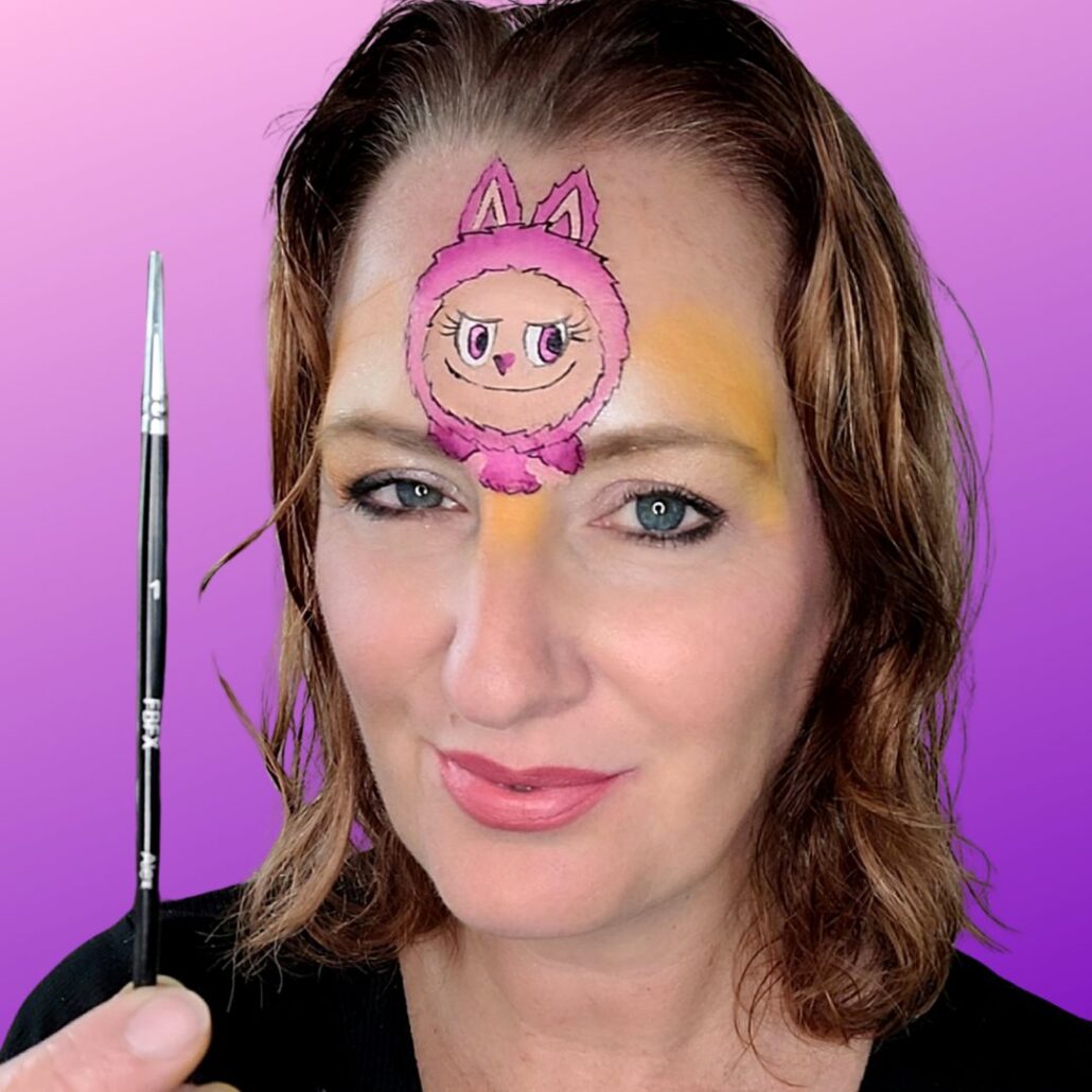 Omlijnen van het gezicht en details van Labubu met een dun penseel voor een speelse Halloween look, gecreëerd met producten van SchminkenGrime.nl