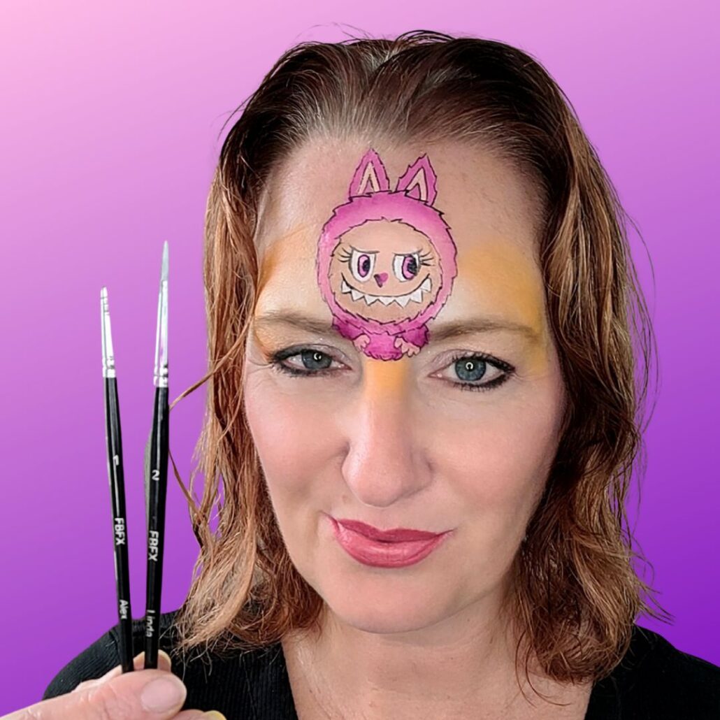 Toevoegen van tanden en expressie aan het Labubu gezichtje met zwarte schmink en twee penselen, voor een karaktervolle monstertje look