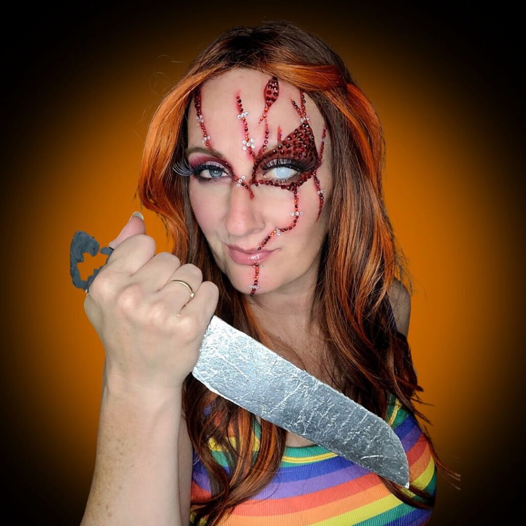 Chucky Halloween make-up eindresultaat met rode wonden en witte lens, glam horror stijl, verkrijgbaar bij SchminkenGrime.nl