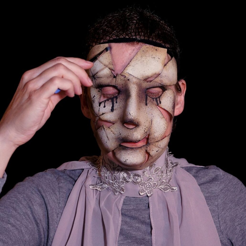 Masker op gezicht afgetekend met zwart oogpotlood voor enge pop schmink