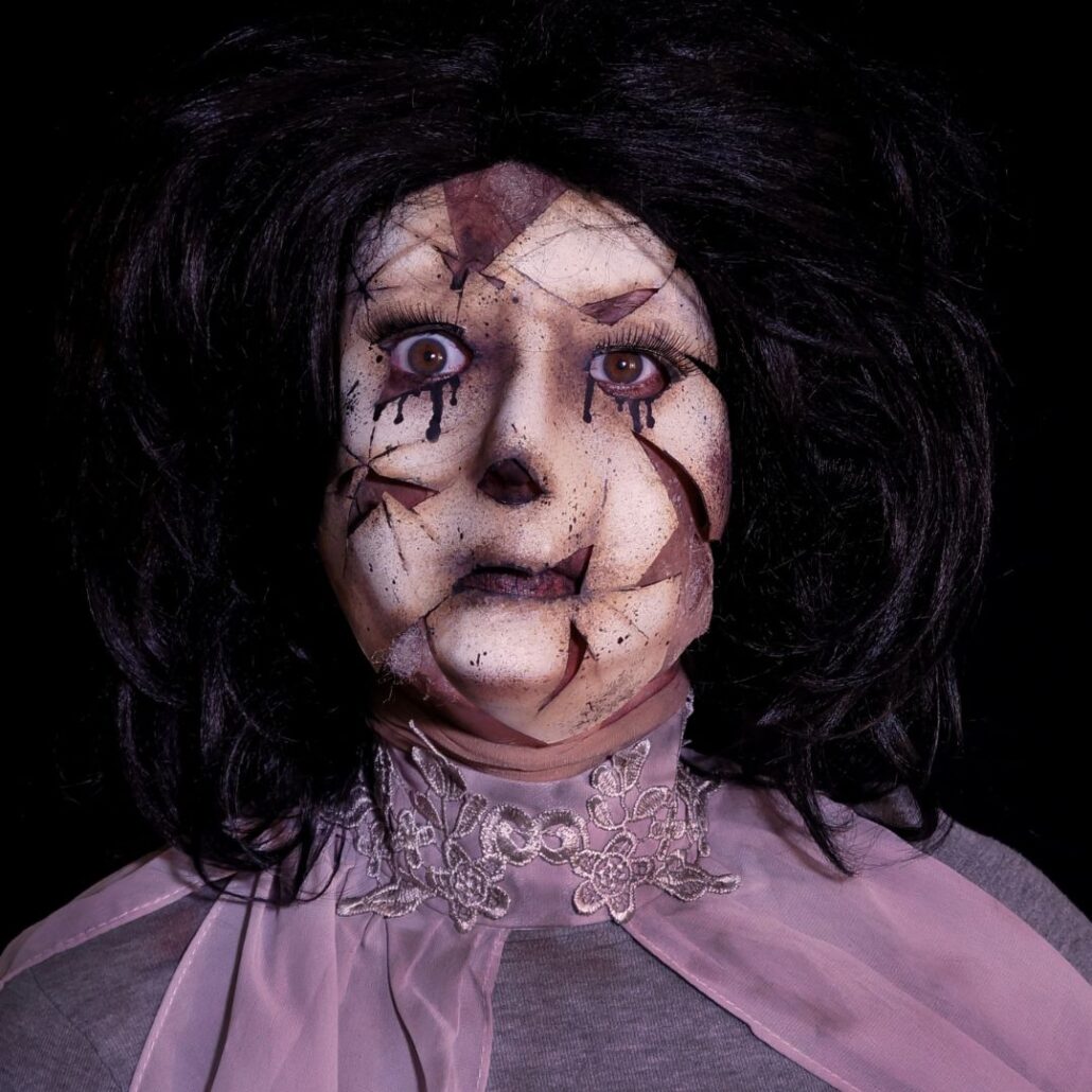 Gebroken porseleinen pop met zwarte tranen en enge Halloween schmink look