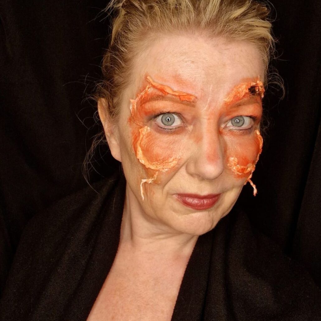 Aanbrengen van oranje en rode schmink over de latexbasis voor de Meat Moth Halloween schmink, door Syl Verberk met producten van SchminkenGrime.nl