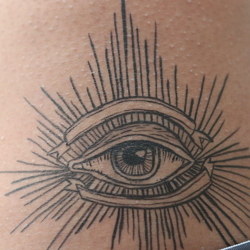 The Crow make-up alziend oog schmink voorbeeld op been, zwart-wit tattoo ontwerp geïnspireerd op Bill Skarsgård, verkrijgbaar bij SchminkenGrime.nl