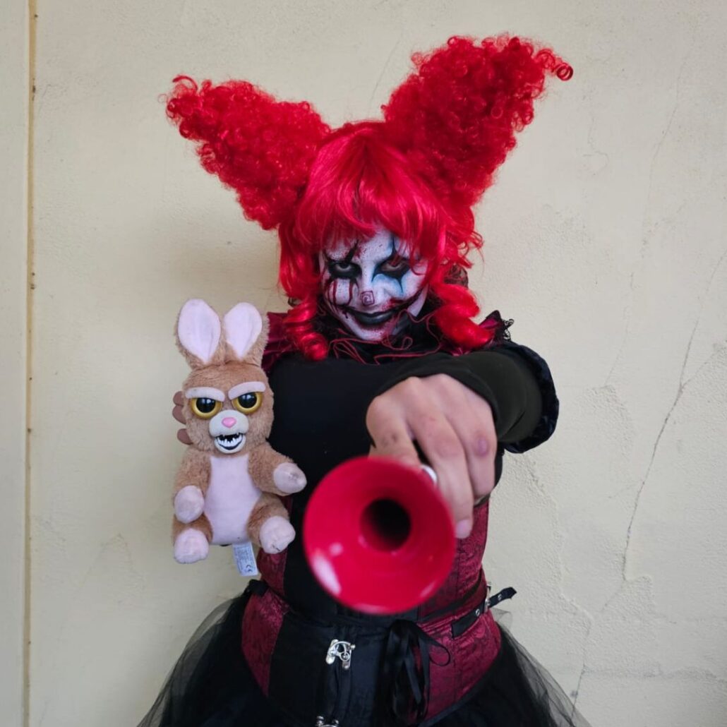 Horrorclown met rode pruik en zwarte make-up bij Halloween The Villains, gegrimeerd door SchminkenGrime.nl, verkrijgbaar bij SchminkenGrime.nl