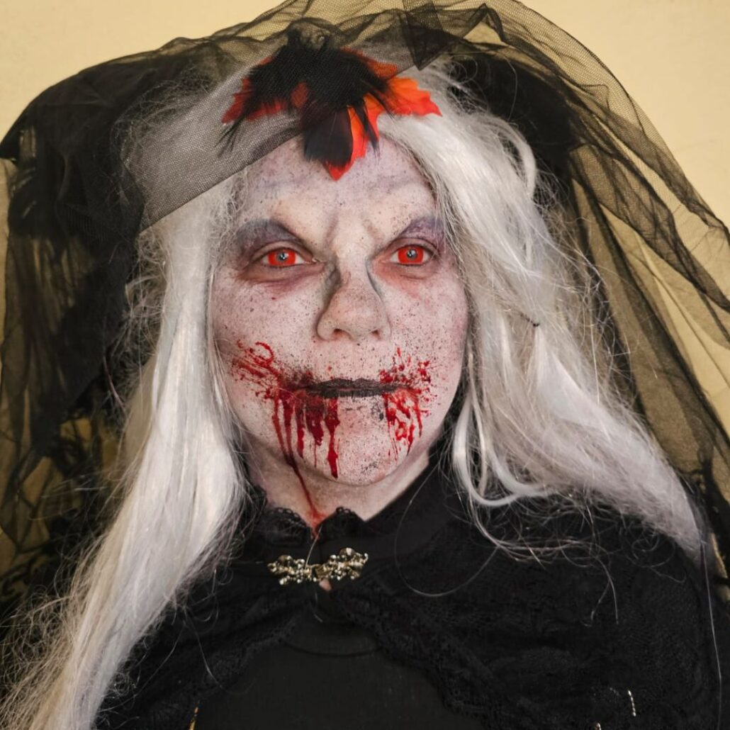 Zombie bruid met witte haren, zwarte sluier en bloedige mond bij Halloween The Villains, gegrimeerd door SchminkenGrime.nl, verkrijgbaar bij SchminkenGrime.nl