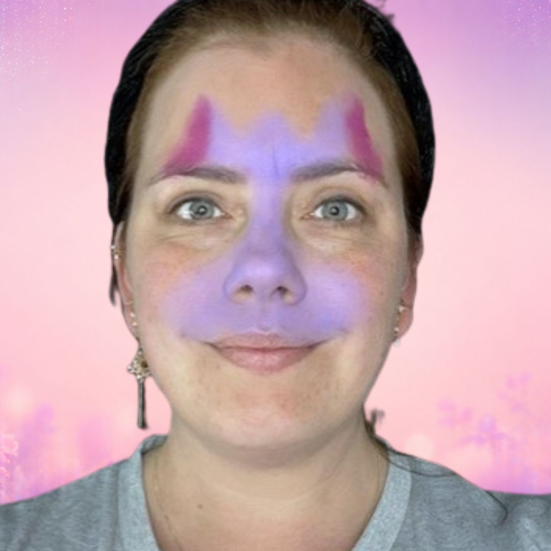 Stap 1 van de kat schminken: basisvorm in paars Lalaland met magenta in de oren en Star Purple op de wangen, aangebracht met een rond sponsje, verkrijgbaar bij SchminkenGrime.nl.
