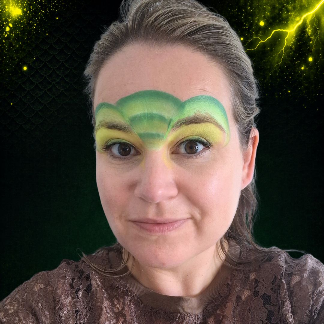 Groene bogen tussen drakenogen geschminkt voor masker-vorm met FBFX Simone schuin penseel en groene splitcake, verkrijgbaar bij SchminkenGrime.nl