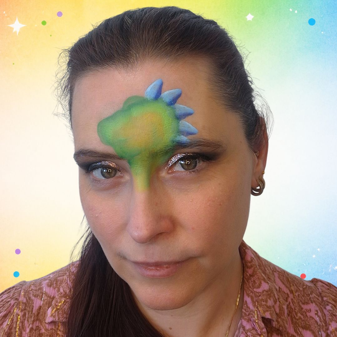 Blauwe Captain Obvious spikes gestempeld langs de bovenkant van de groene dino-kop met FBFX Poem bloemenpenseel, verkrijgbaar bij SchminkenGrime.nl