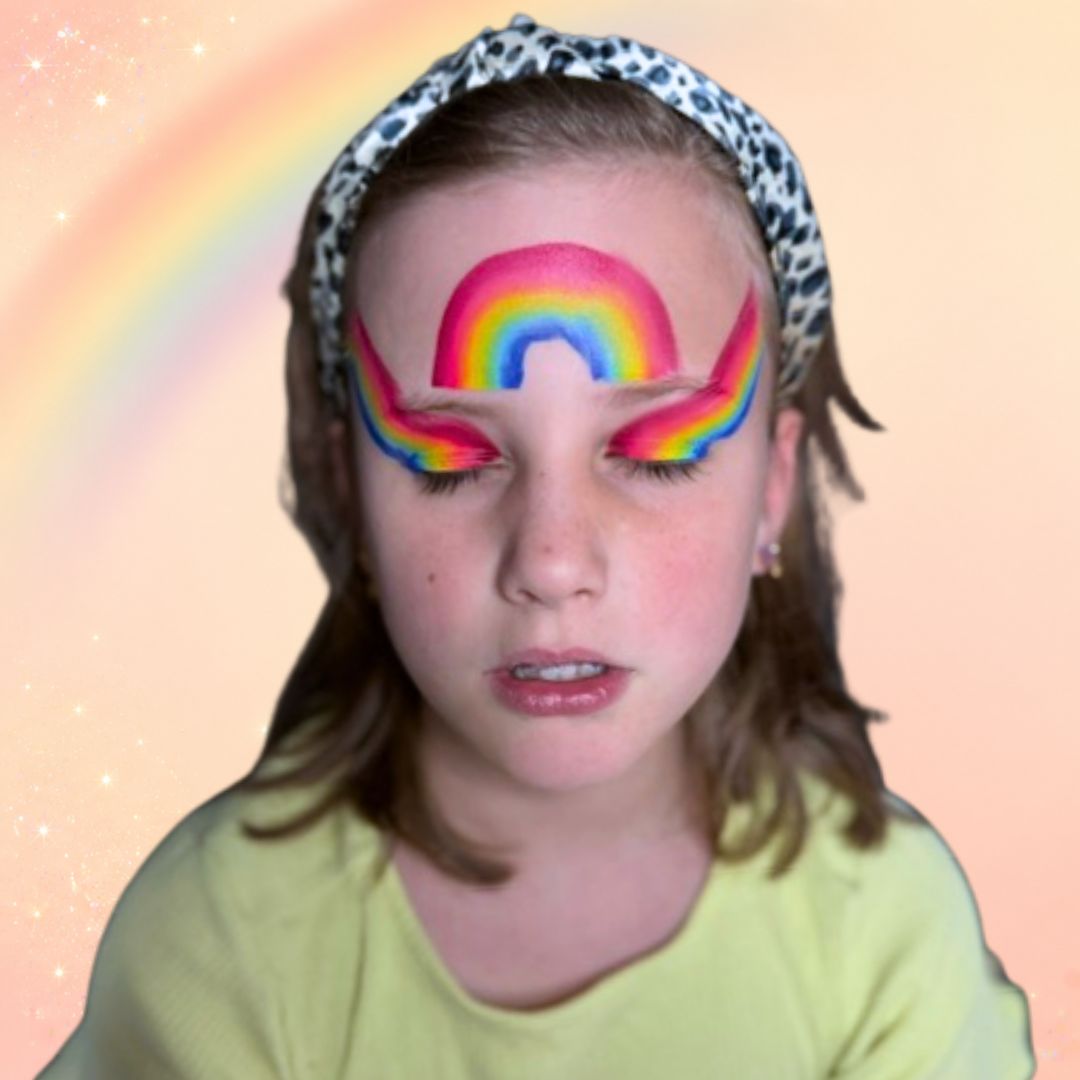 Stap 3 van de regenboog schminken: kleine witte stipjes in en rond de bloem en sierlijke witte druppels boven de bloem en rondom de ogen, gezet met de FBFX Linda 5, verkrijgbaar bij SchminkenGrime.nl.