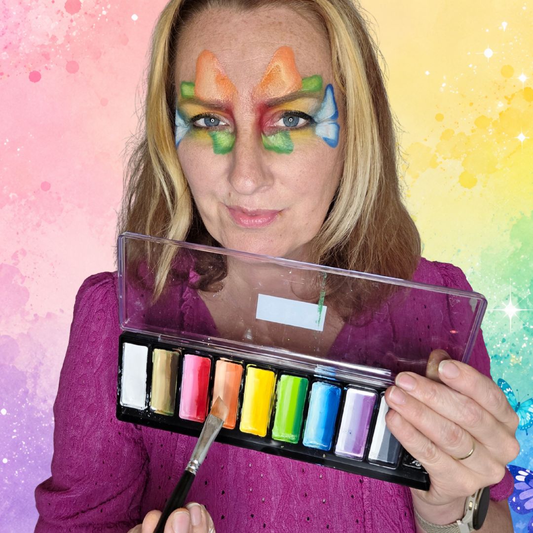 Oranje vleugels van een regenboog vlinder op het voorhoofd boven de wenkbrauwen, iets groter dan de blauwe en groene vleugels, verkrijgbaar bij SchminkenGrime.nl.