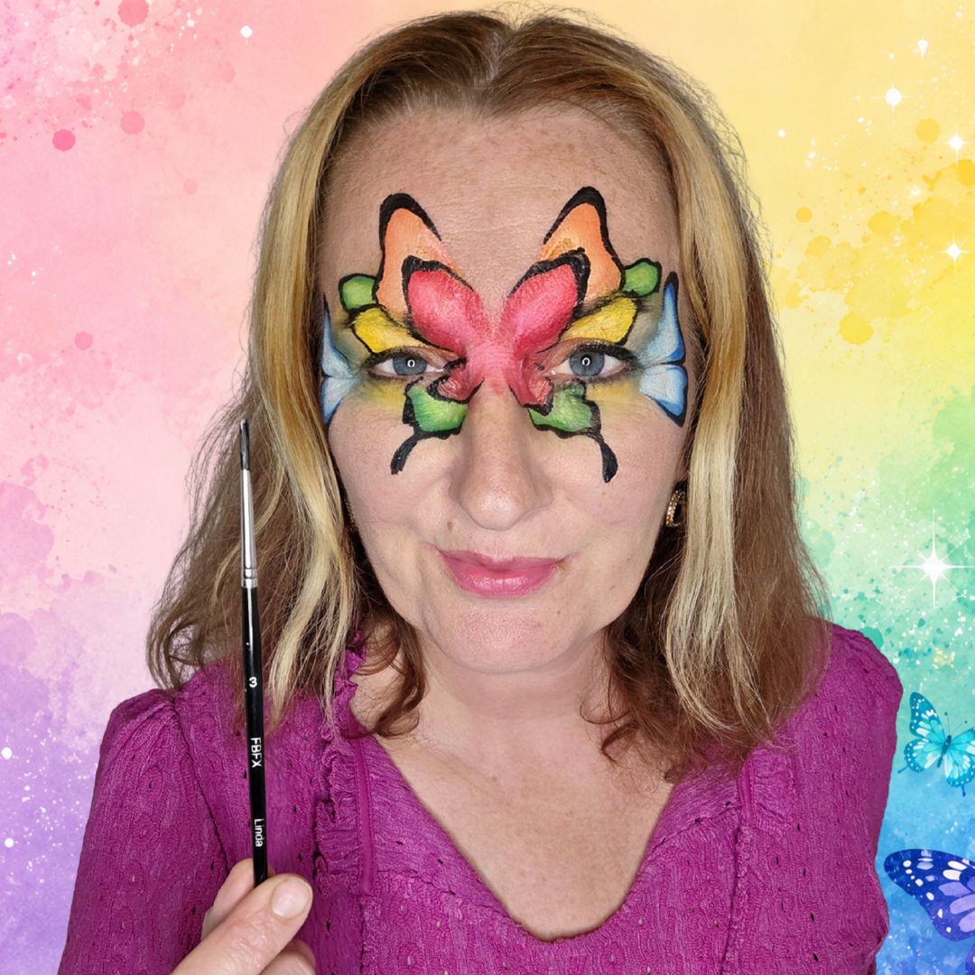 Zwart lijnwerk om de regenboog-vleugels heen met dunne en dikkere lijnen en aflopende druppels voor een dramatisch effect, gezet met de FBFX Linda 3 rond penseel, verkrijgbaar bij SchminkenGrime.nl.