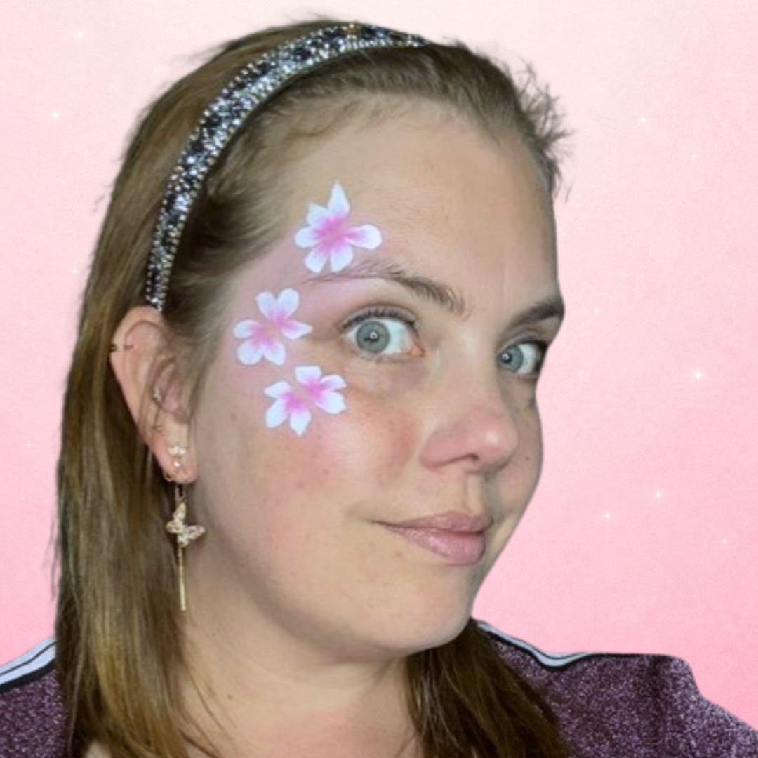 Roze vlindervleugels gestempeld met een bloemenpenseel in wit en cerise rond het oog op een zachtroze ondergrond, verkrijgbaar bij SchminkenGrime.nl