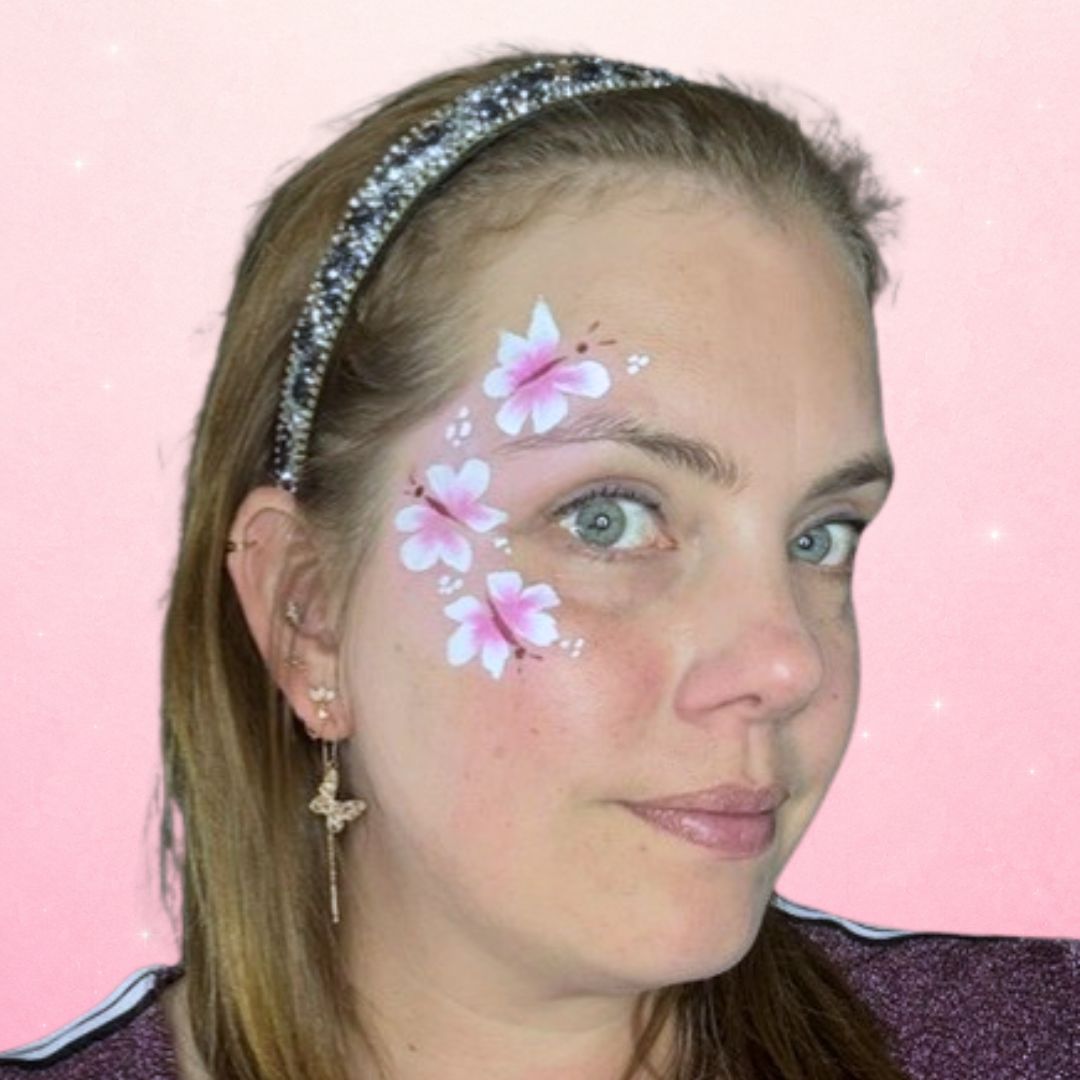 Fijne witte stippen rond de roze vlinders die het cheek art design tot een geheel maken, verkrijgbaar bij SchminkenGrime.nl