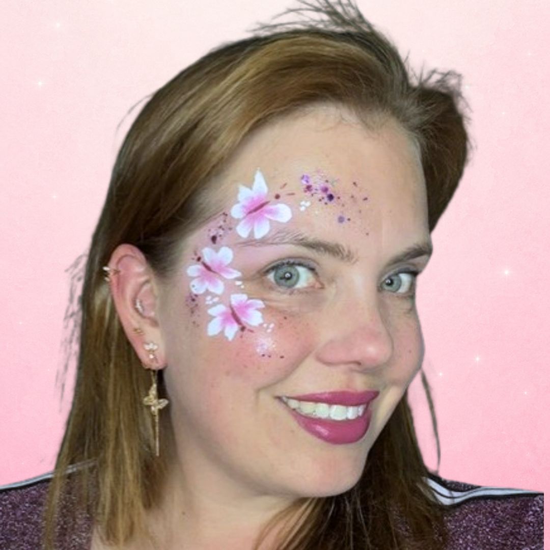 Afgewerkte cheek art vlinders rond het oog met glitter en zachtpaarse accenten als finishing touch, verkrijgbaar bij SchminkenGrime.nl