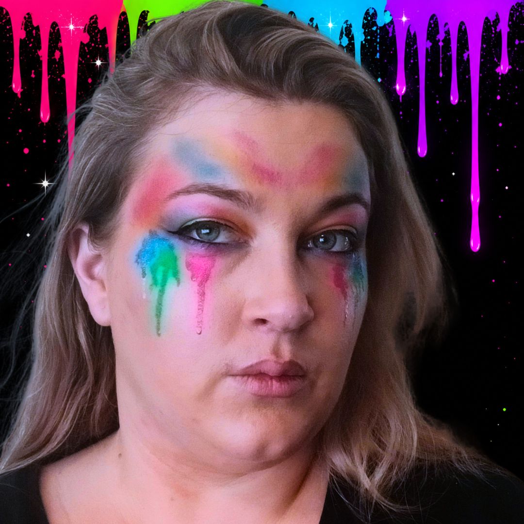 De neon druppels onder beide ogen met de eerste kleuren aangebracht op het voorhoofd als basis voor de steentjes, verkrijgbaar bij SchminkenGrime.nl.