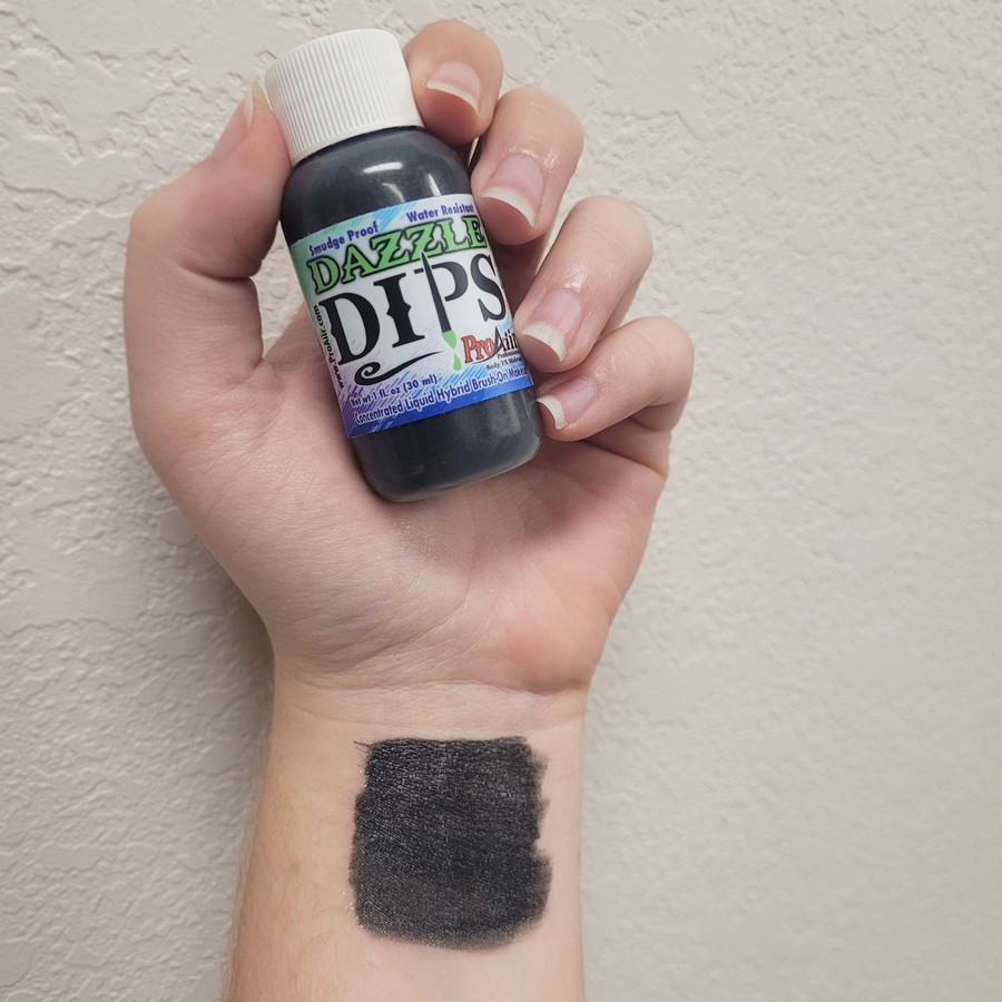 ProAiir Dazzle Dips Black swatch – metallic schmink | SchminkenGrime.nl Swatch van ProAiir Dazzle Dips Black op de huid, glanzend zwarte schmink, verkrijgbaar bij SchminkenGrime.nl