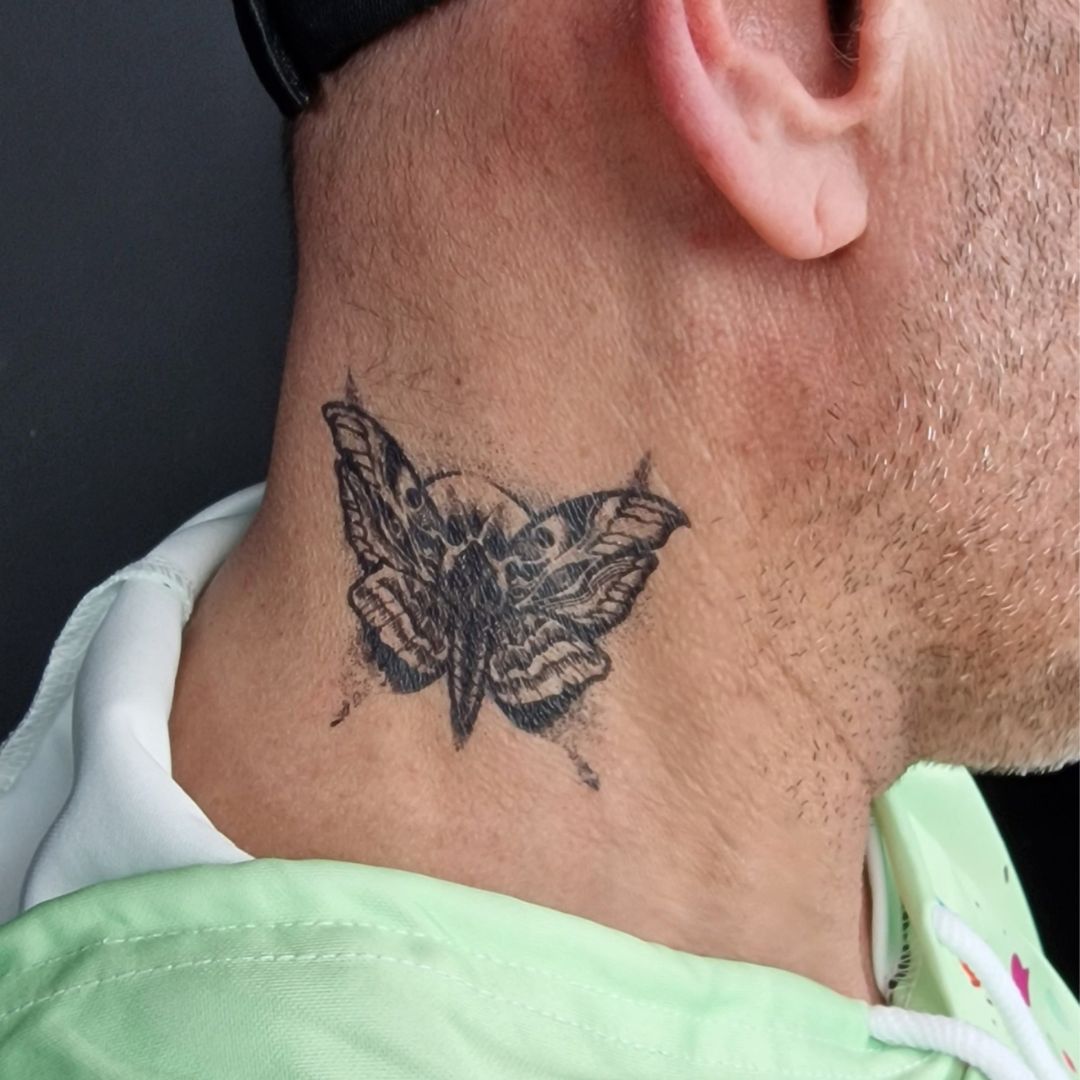 Zwarte Quick Tattoo van een vlinder aangebracht op de nek, tijdelijk tattoo-effect met gedetailleerd ontwerp, verkrijgbaar bij SchminkenGrime.nl