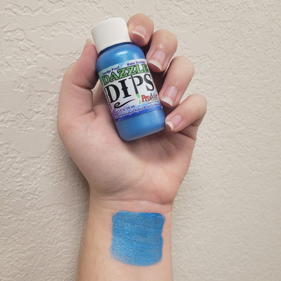 ProAiir Dazzle Dips Blue swatch op huid – metallic schmink | SchminkenGrime.nl Swatch van ProAiir Dazzle Dips Blue op huid, metallic blauwe glans, verkrijgbaar bij SchminkenGrime.nl