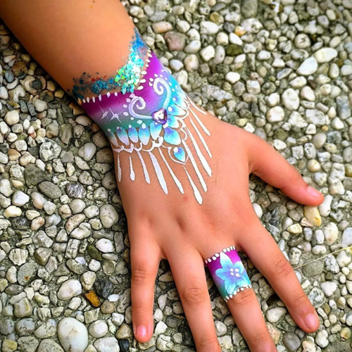 Sierlijk pols-ontwerp in paars en turquoise met witte kantdetails en glitter, geschminkt met producten van SchminkenGrime.nl
